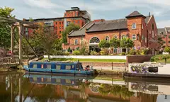 The Castlefield canal in Manchester, with a narrowboat moored in front of old brick warehouses
