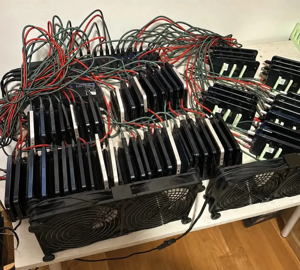 Table with dozens of mobile phones on stands, wired up and air-cooled: part of the Luzara Talent phone farm