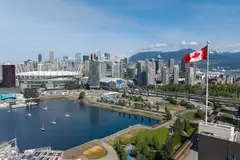 Downtown Vancouver by False Creek, with BC Place stadium, a Canadian flag and mountains behind